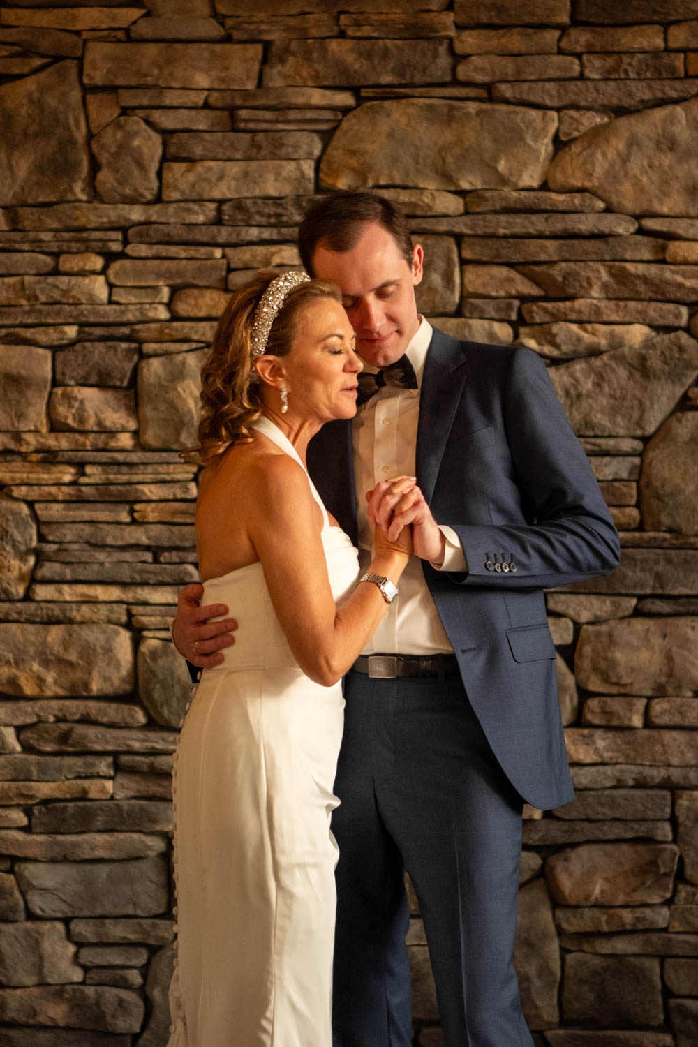 bride leans her head on her son's shoulder while they dance during her wedding reception