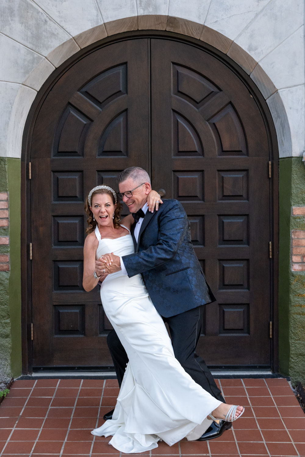 groom dips bride as she smiles openly