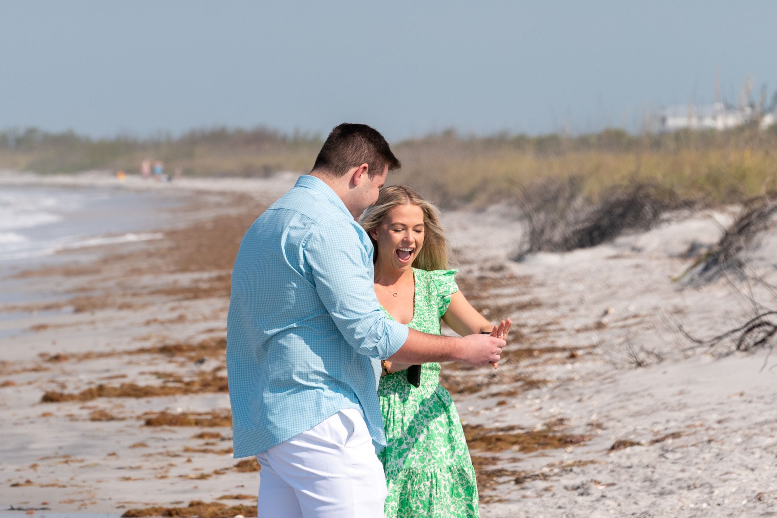 newly engaged couple hold out her hand to look at her new engagement ring