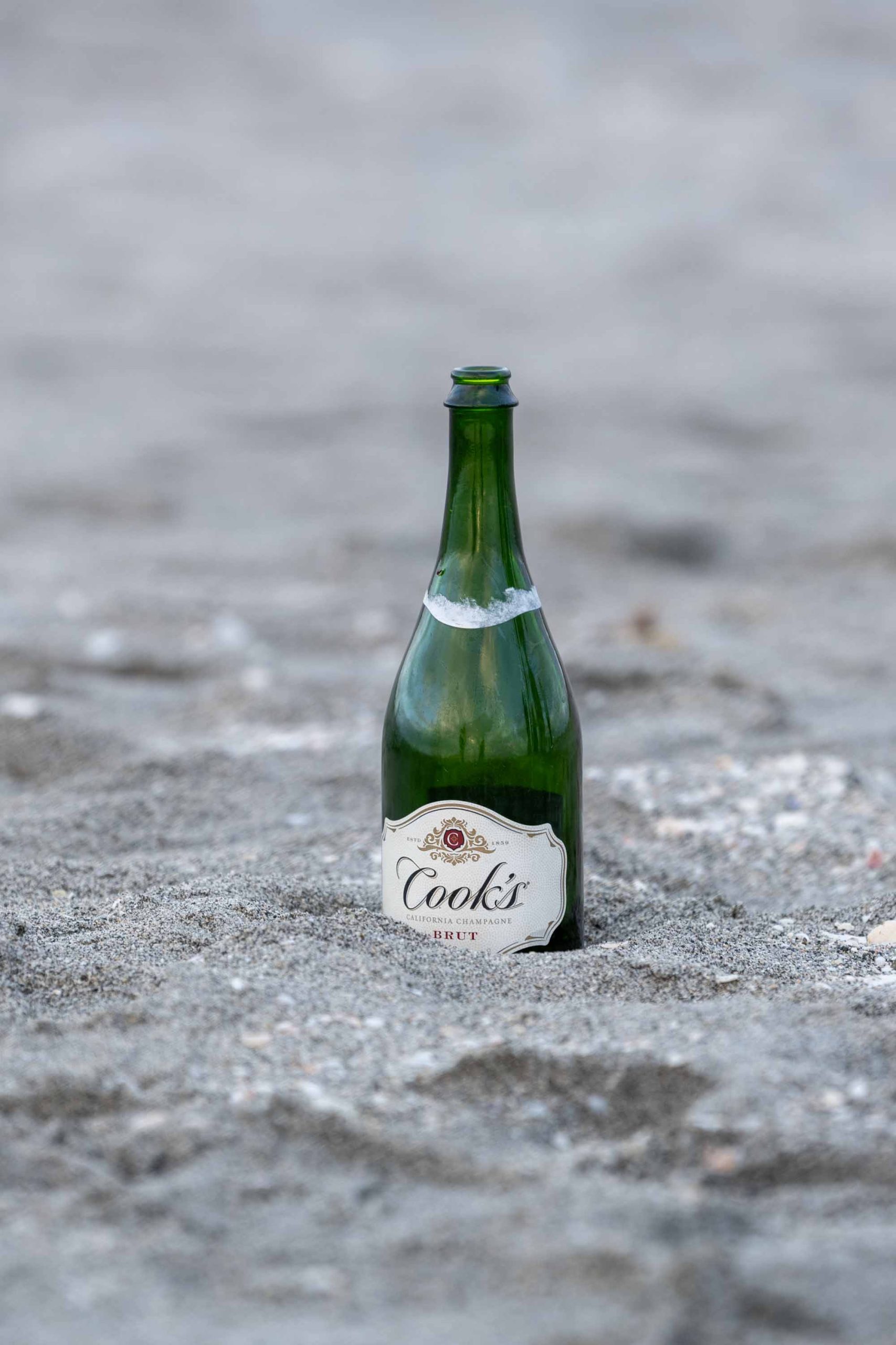 bottle of champagne sitting in the sand