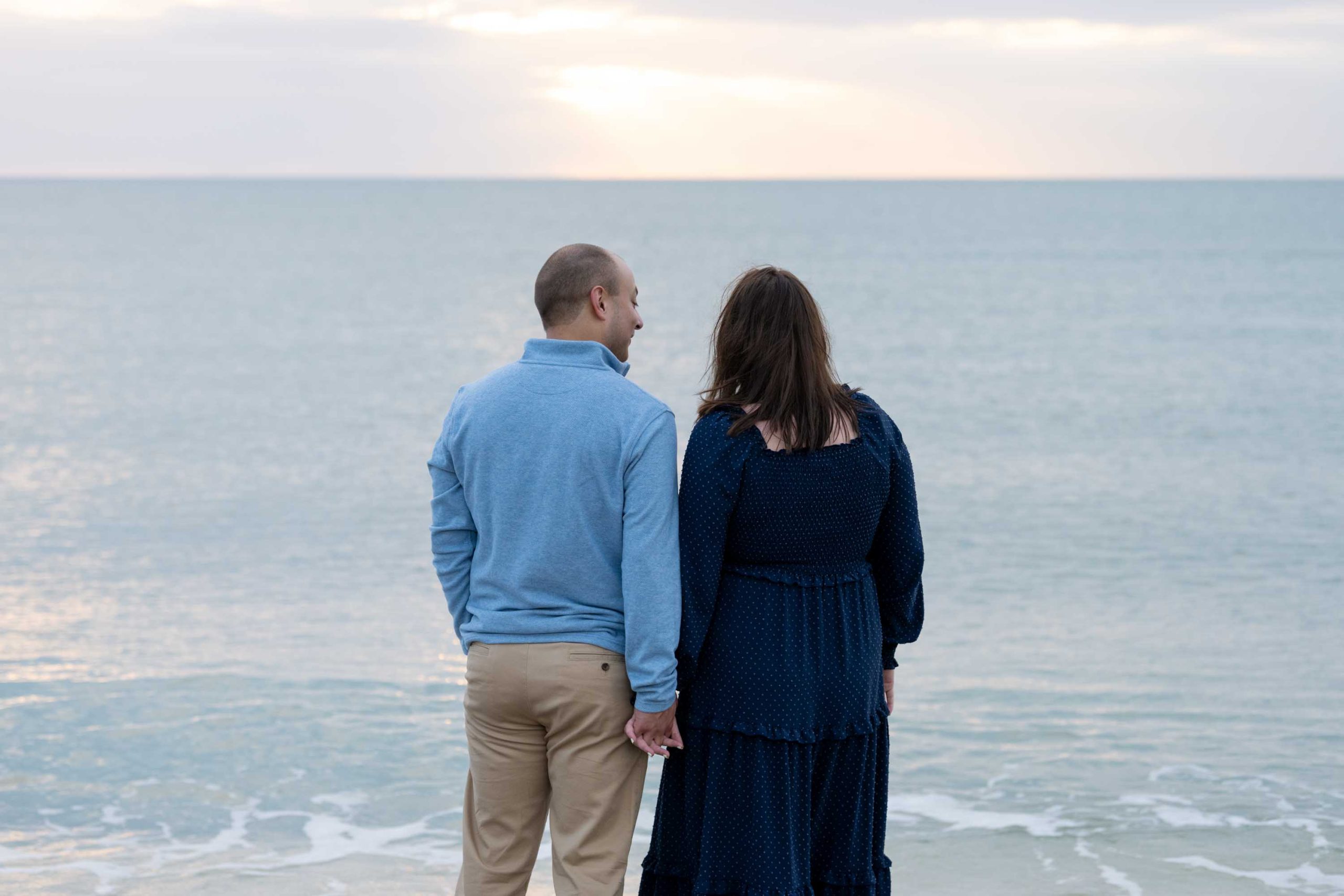 engaged couple watch the sunset on the beach