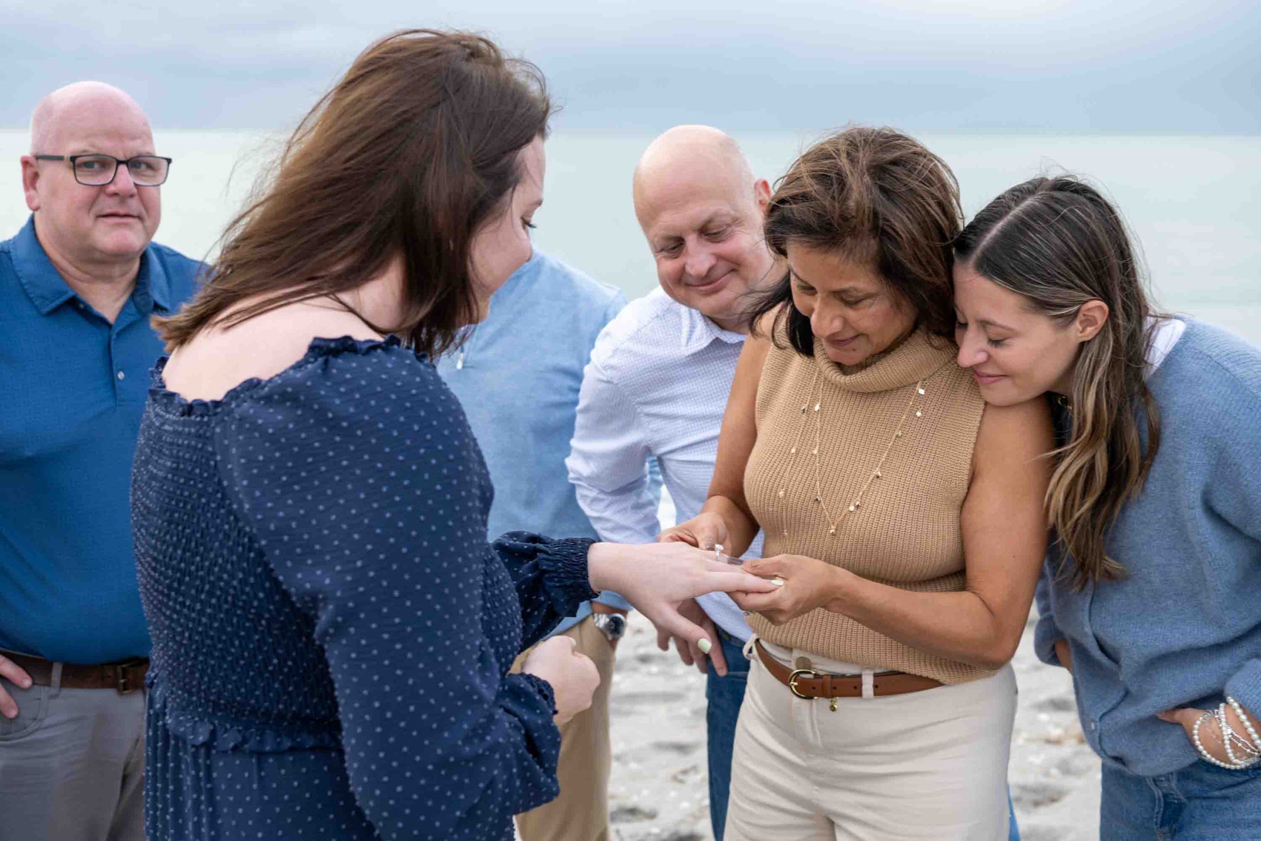 groom's mother looks at the engagement ring as everyone looks on