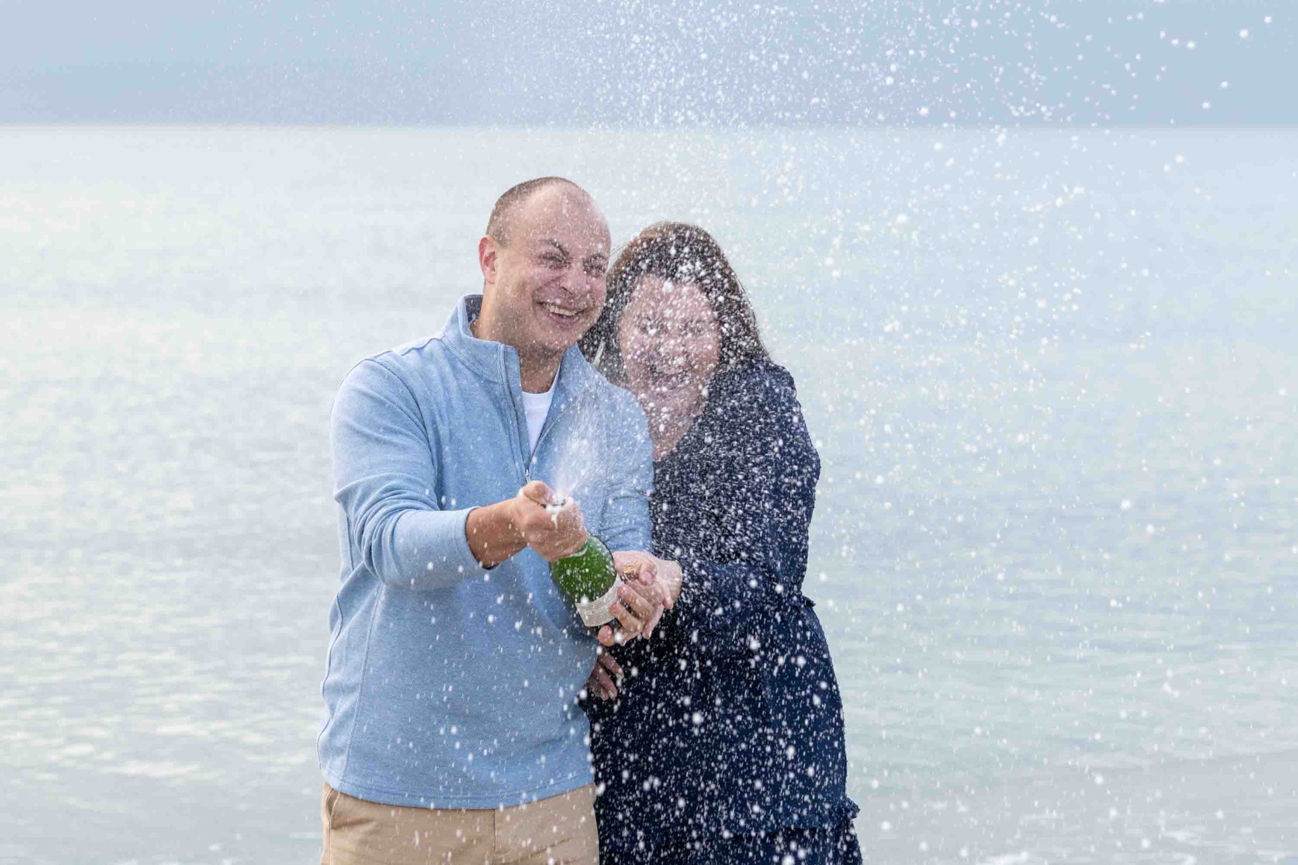 couple celebrate their surprise Venice Beach engagement with a bottle of champagne