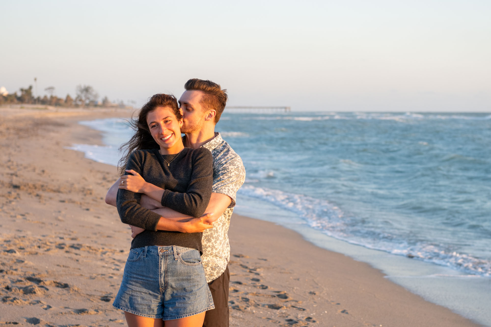 guy kisses his girlfriend's neck as he embraces her