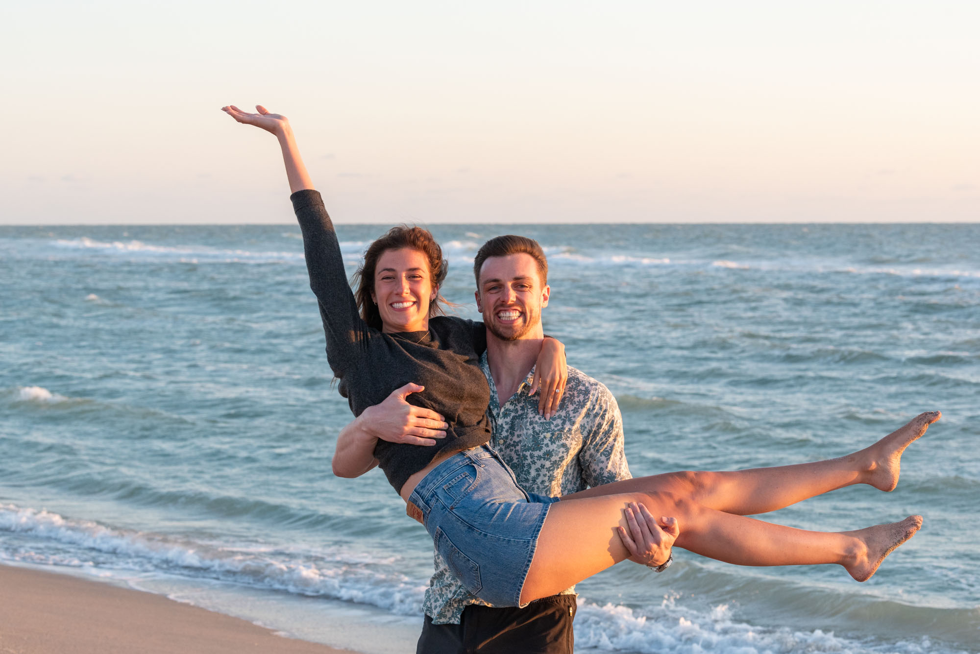 guy picks up his girlfriend as she throws her arm in the air