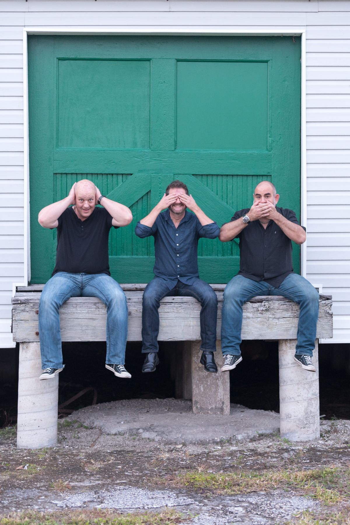 The Monsoons making fun of themselves while sitting in front of a green door