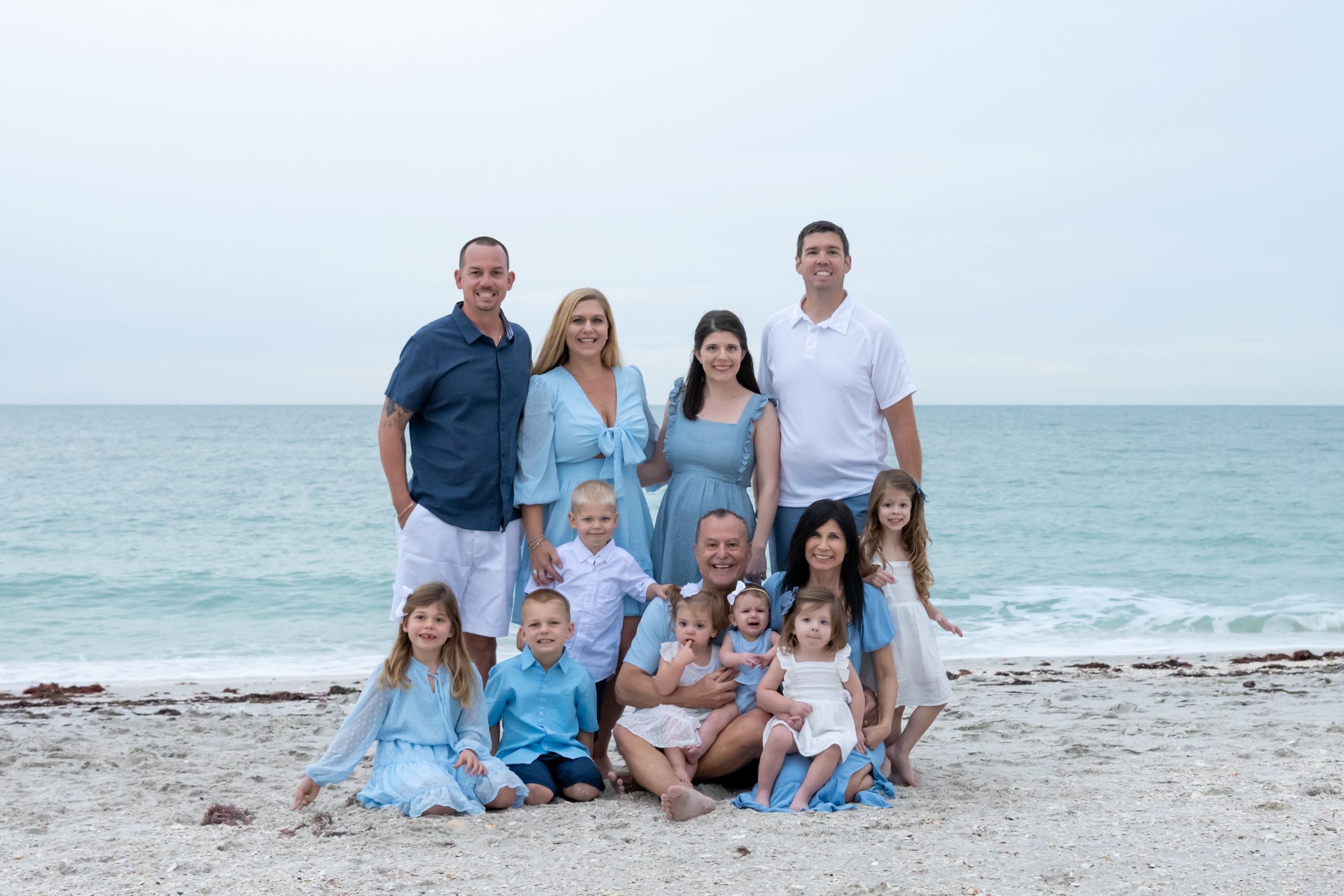 large family standing and sitting on the beach