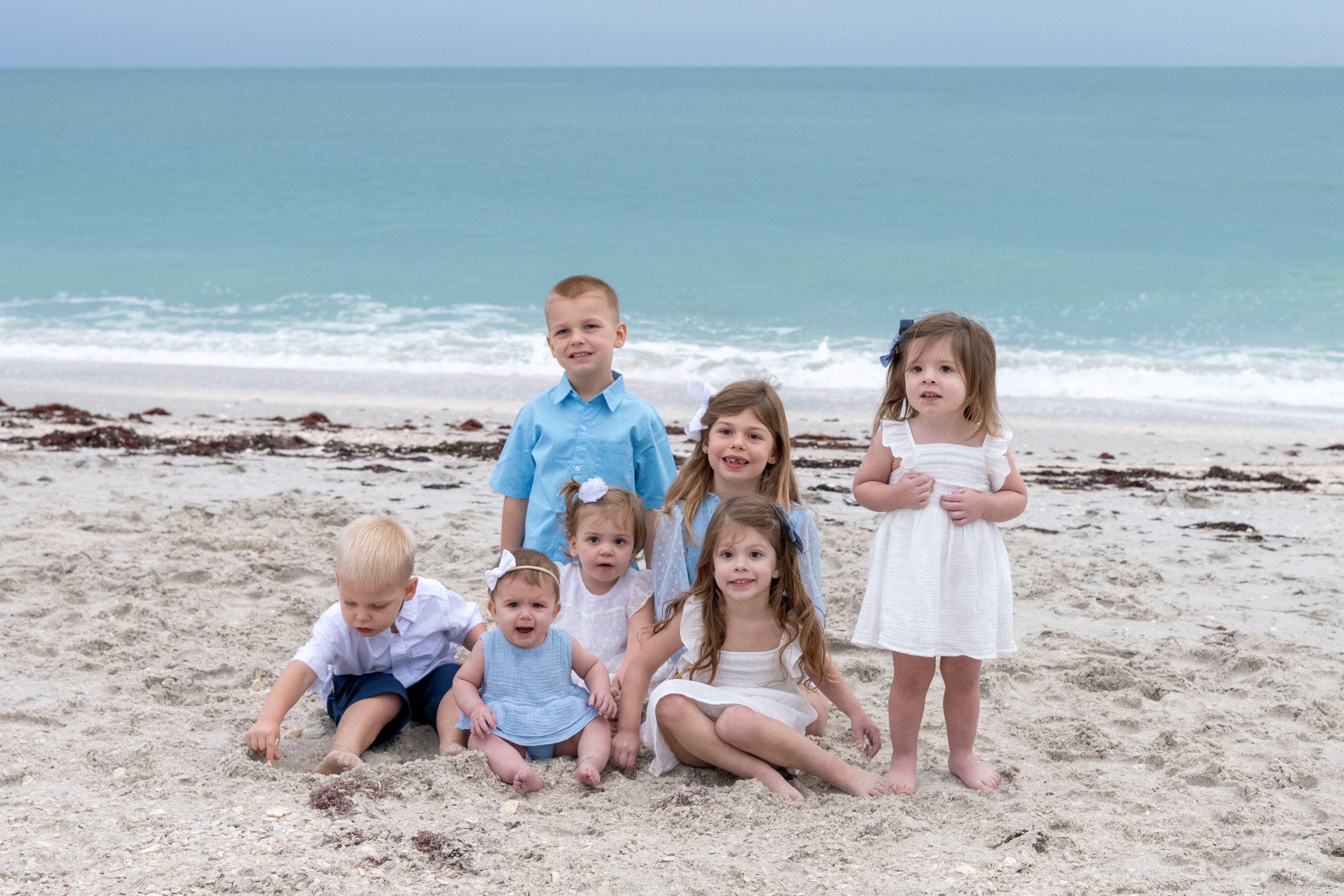 seven young children sitting and playing on the beach