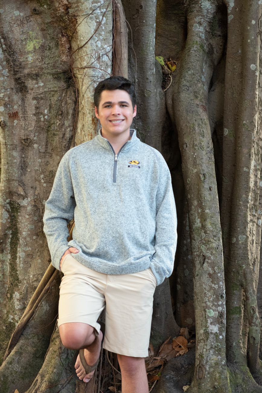 senior boy standing in front of a banyan tree