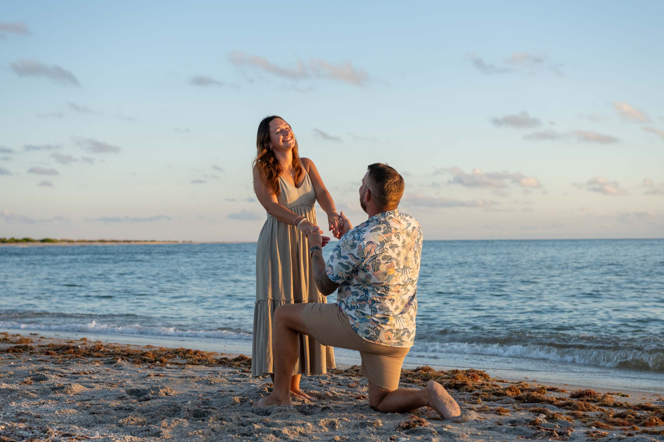 surprise proposal on Stump Pass beach with man on his knee proposing