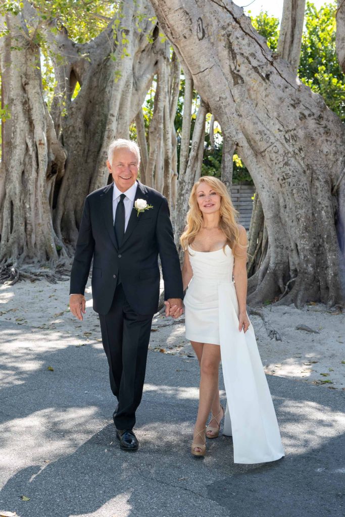 bride and groom hold hands walking along street