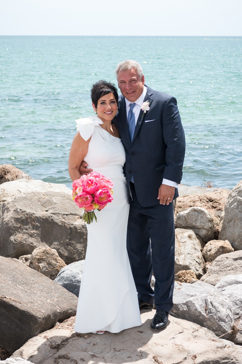 mature bride and groom stand together on boulders