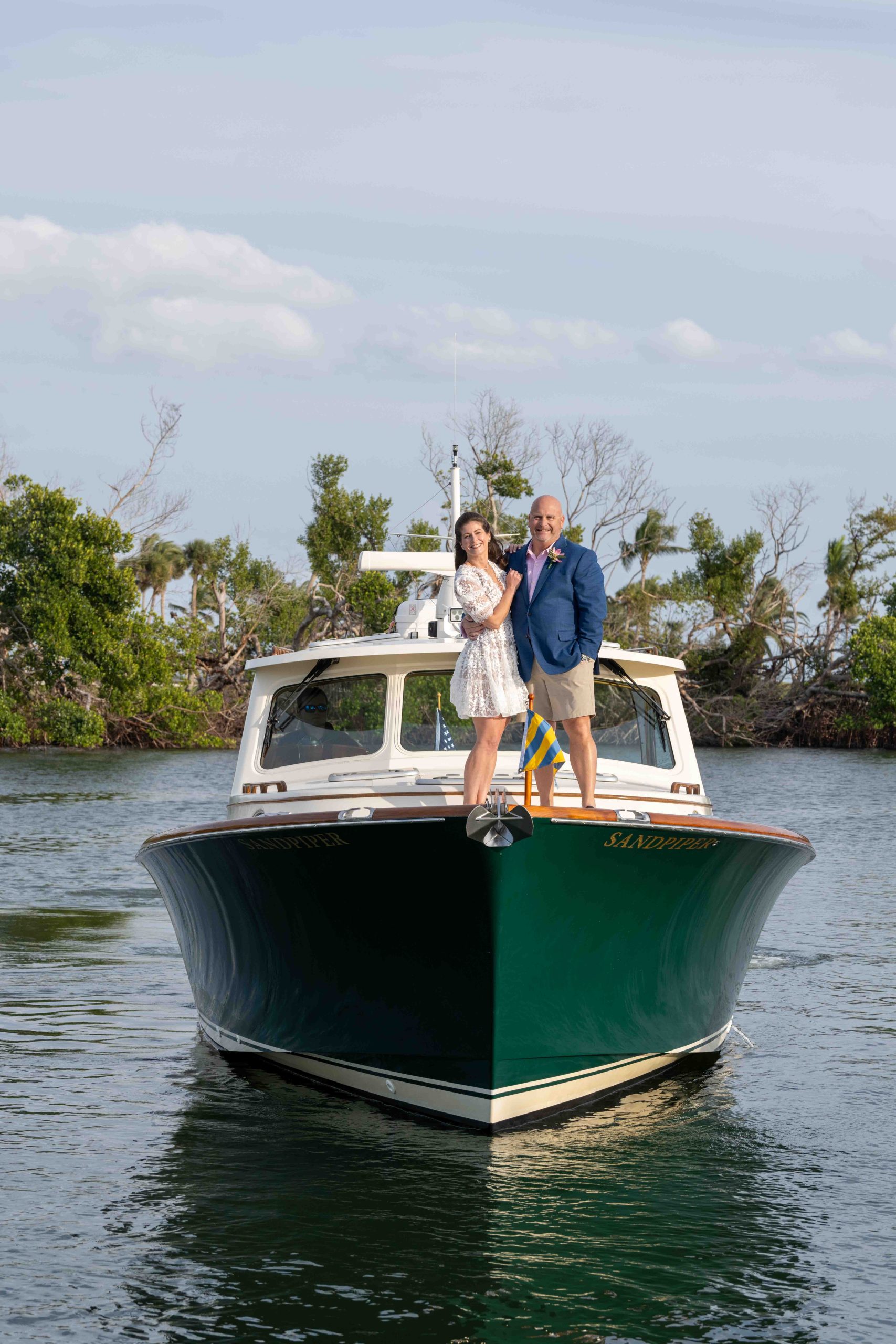 Bride and groom stand on the front of a yacht before their wedding