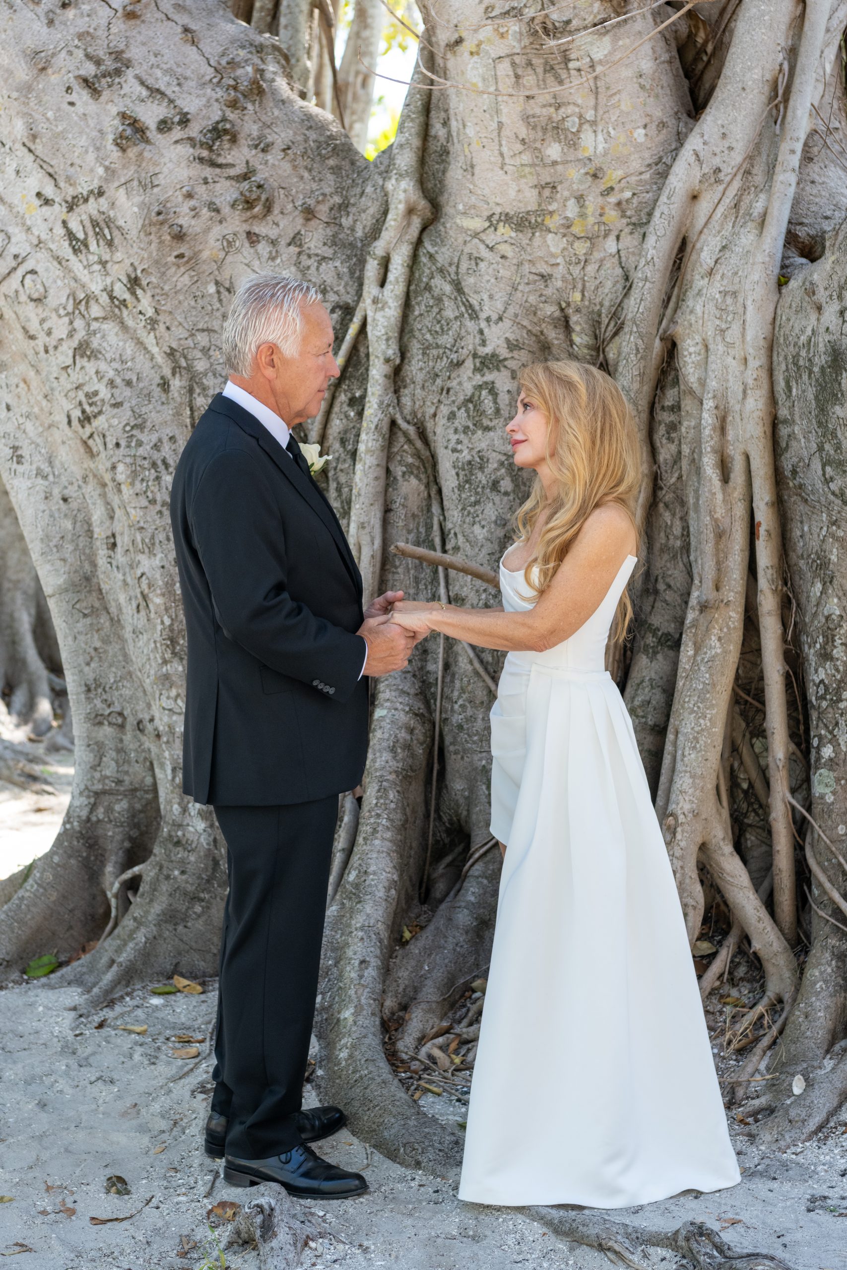 wedding ceremony in front of a tree with groom holding bride's hand