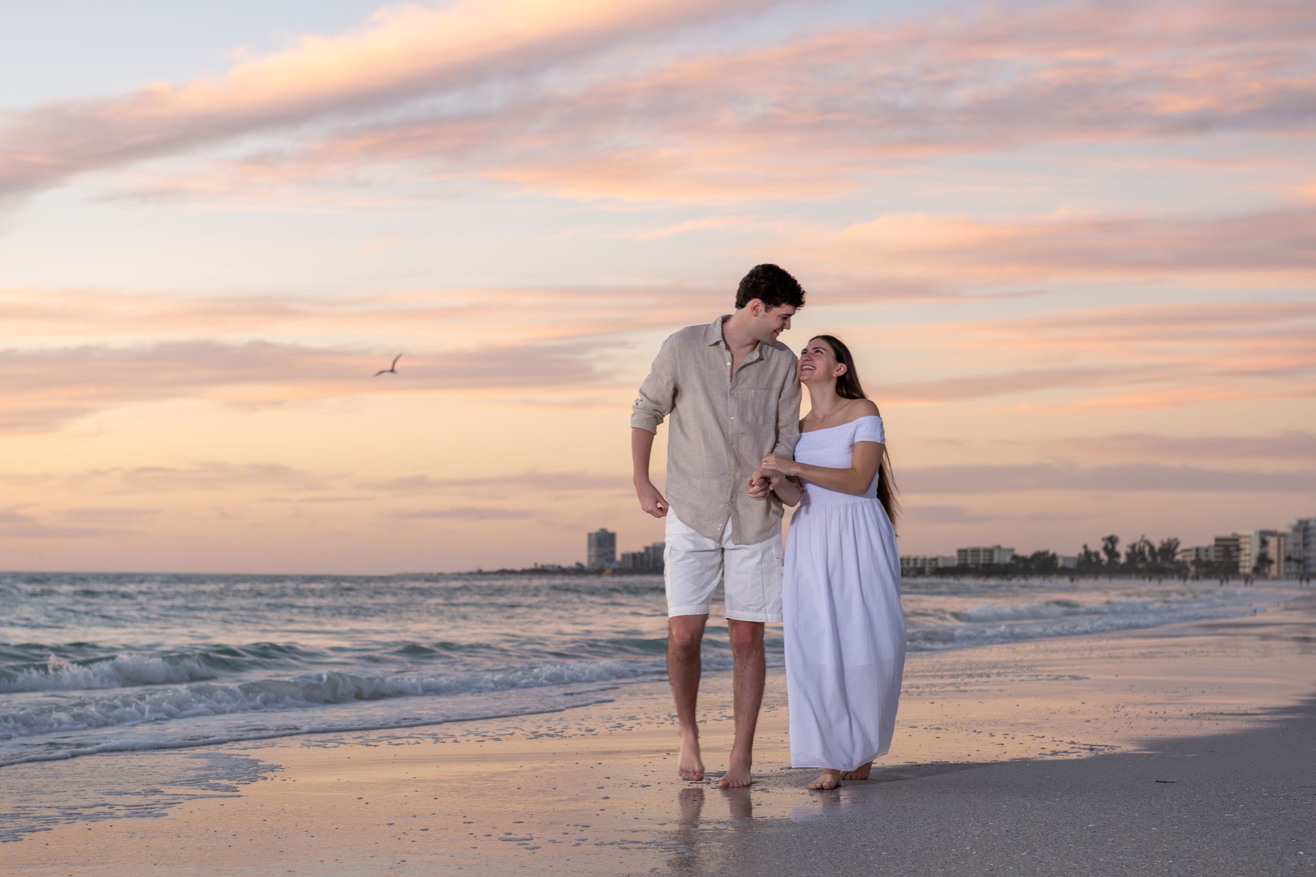 young couple walk hand in hand at sunset on Siesta Key