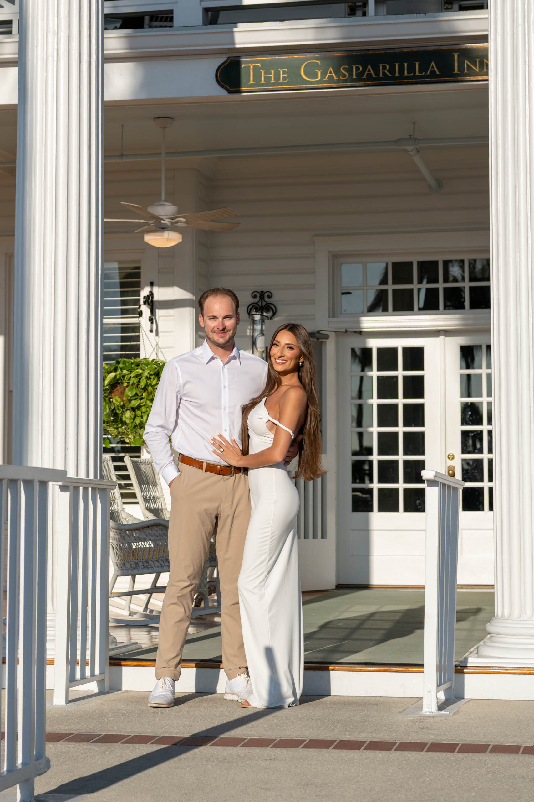 couple stand on the front porch of the Gasparilla Inn during engagement photo session