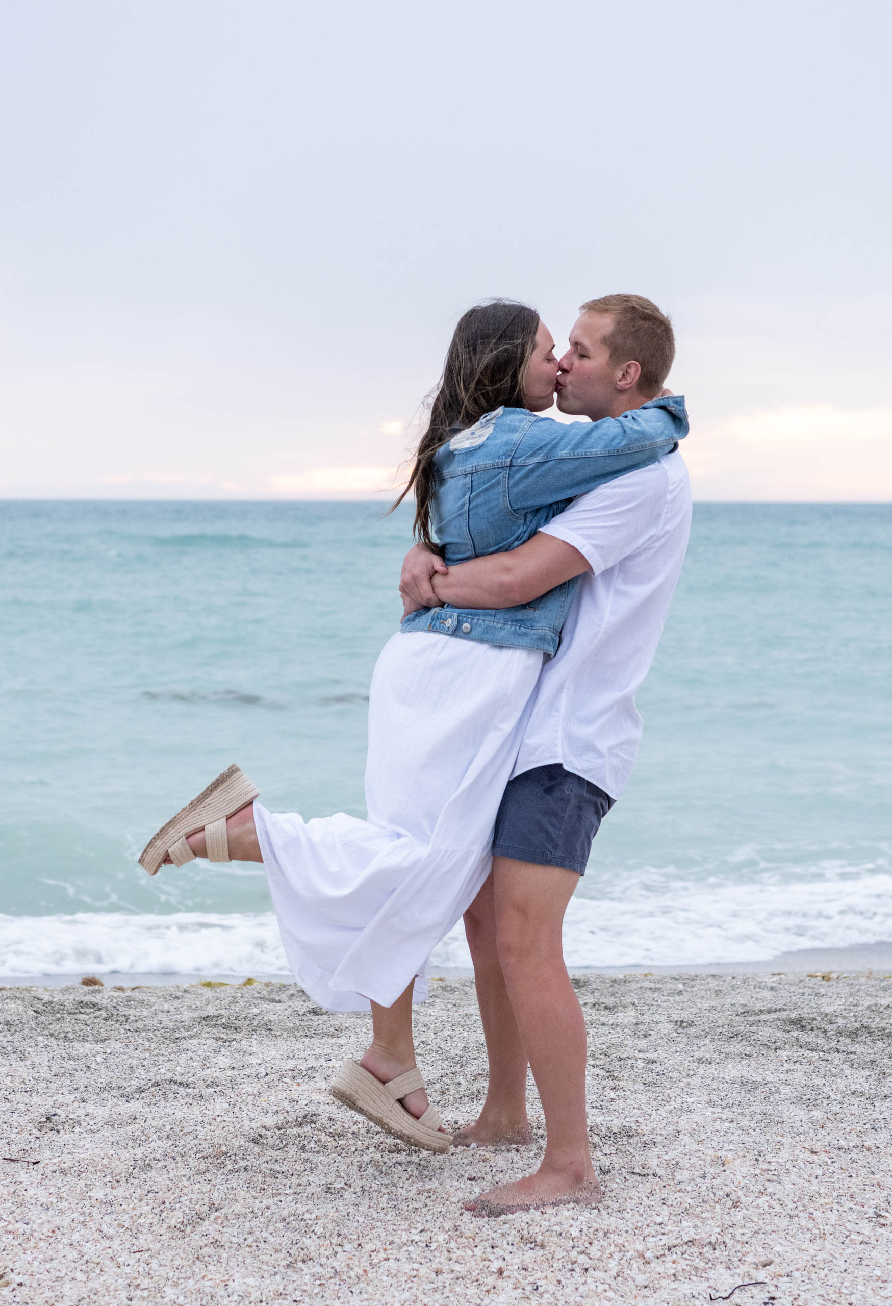 engaged couple kiss on the beach