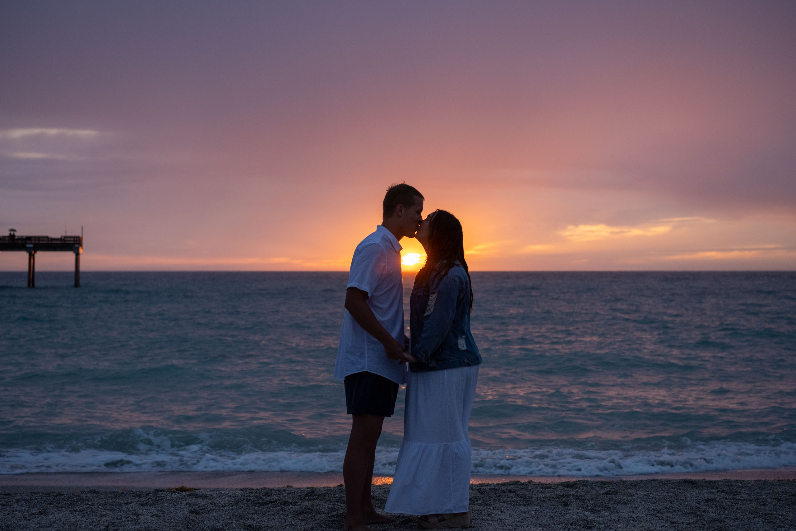 pink sunset after a storm as a couple kiss