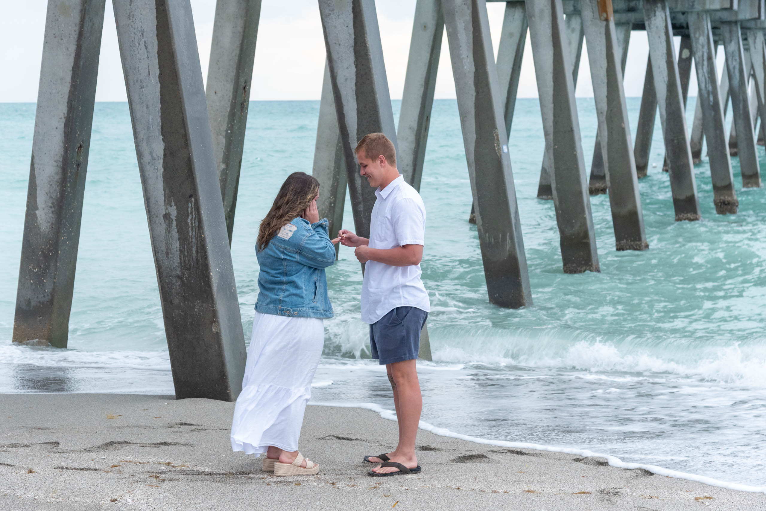 man smiles as he puts wedding ring on his girlfriends finger