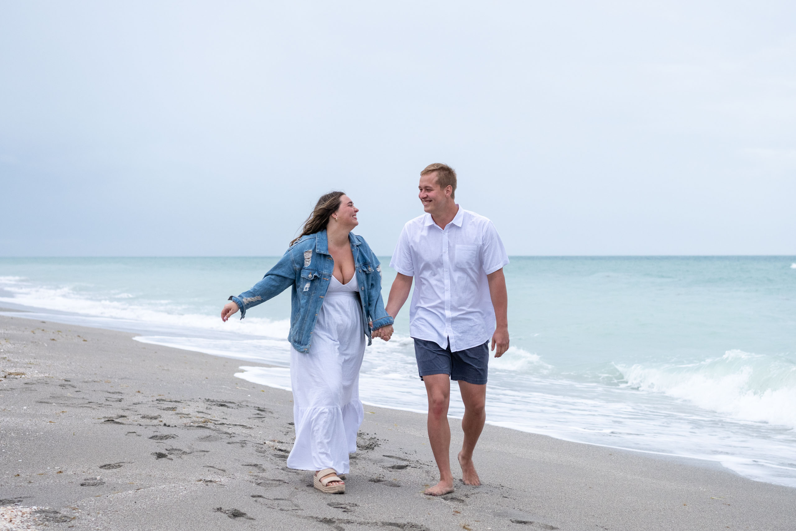 couple walk along the beach on a cloudy night