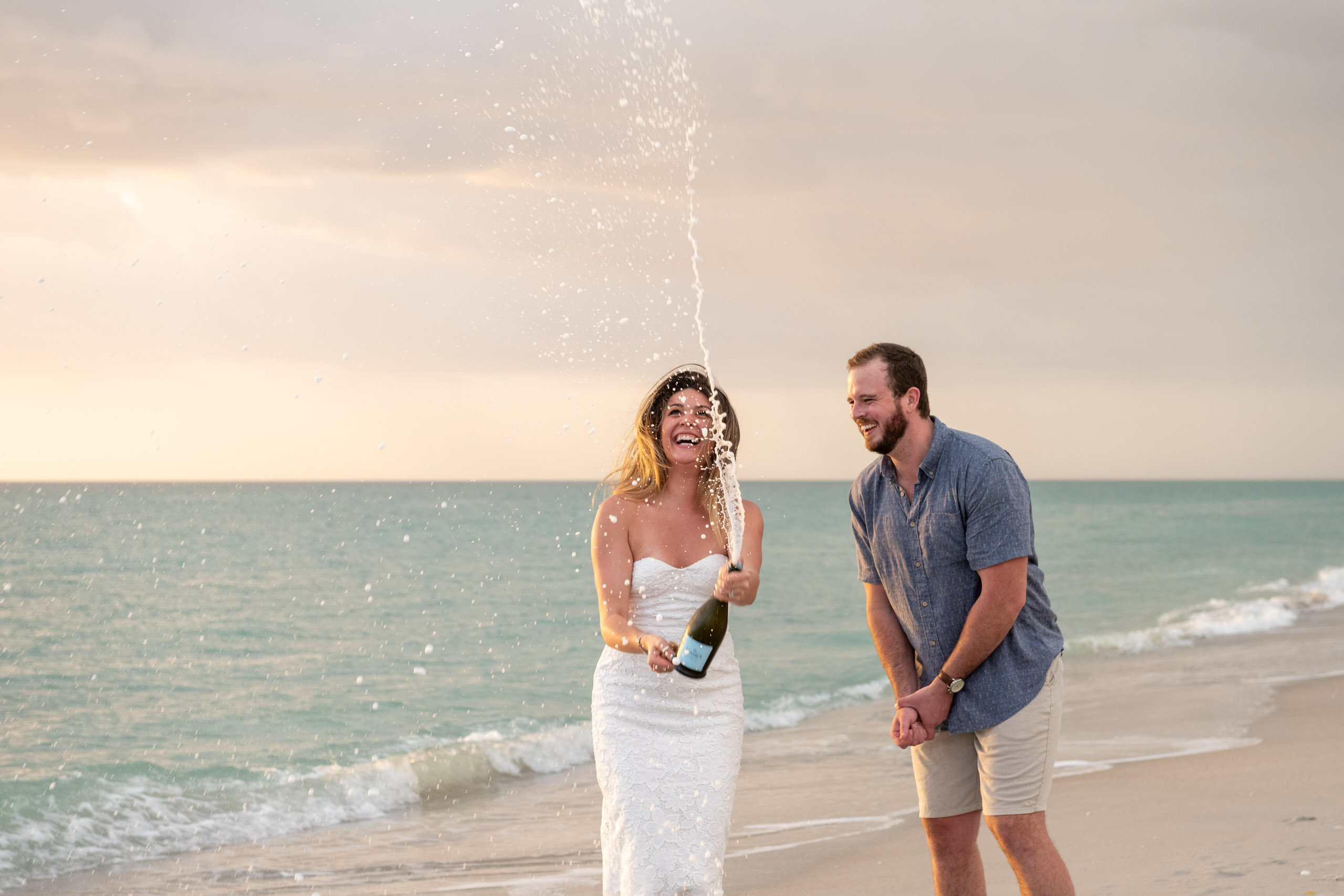 newly engaged couple celebrate with champagne at sunset on Blind Pass Beach