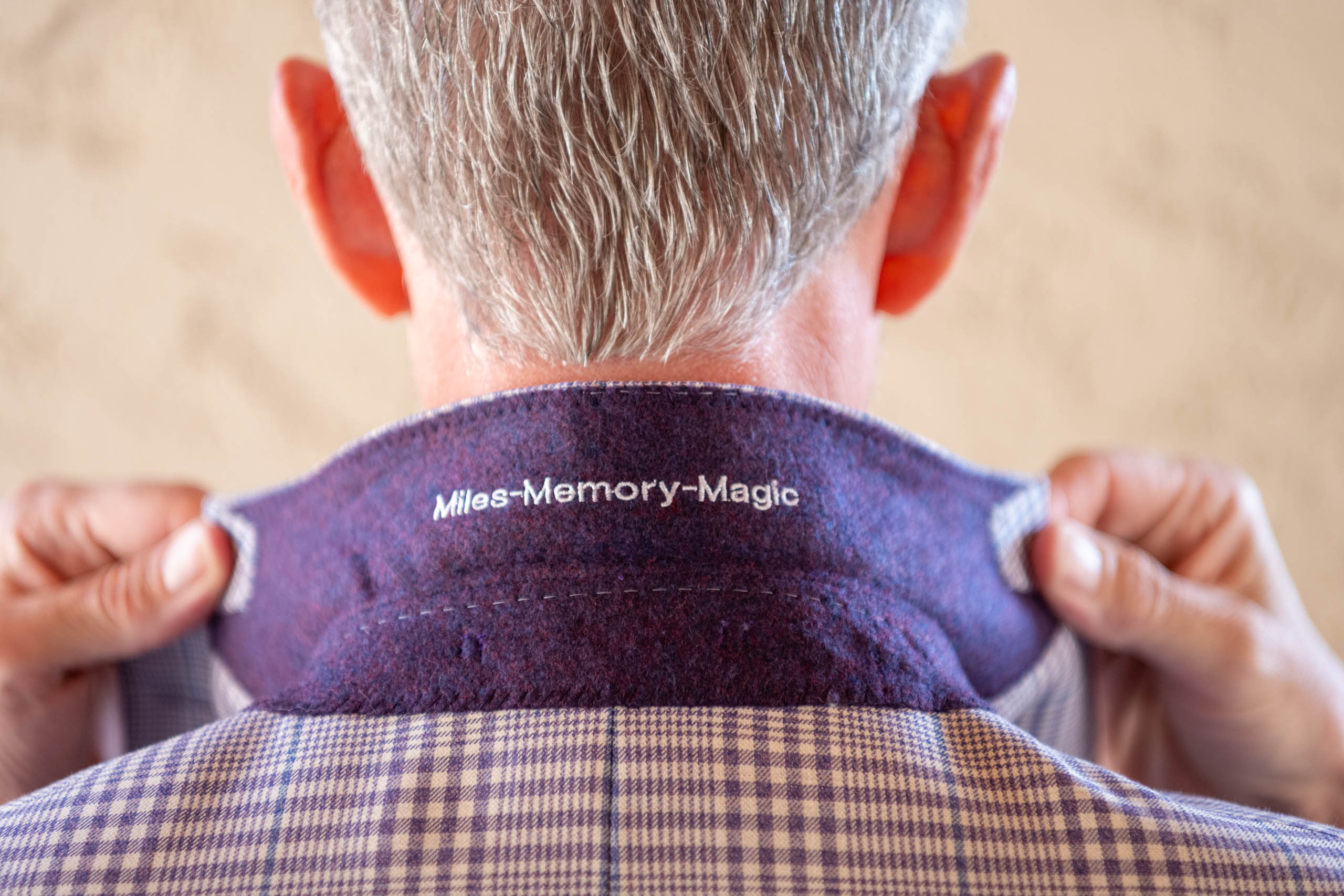 groom shows off custom embroidery on the back of his suit, it says Miles-Memory-Magic