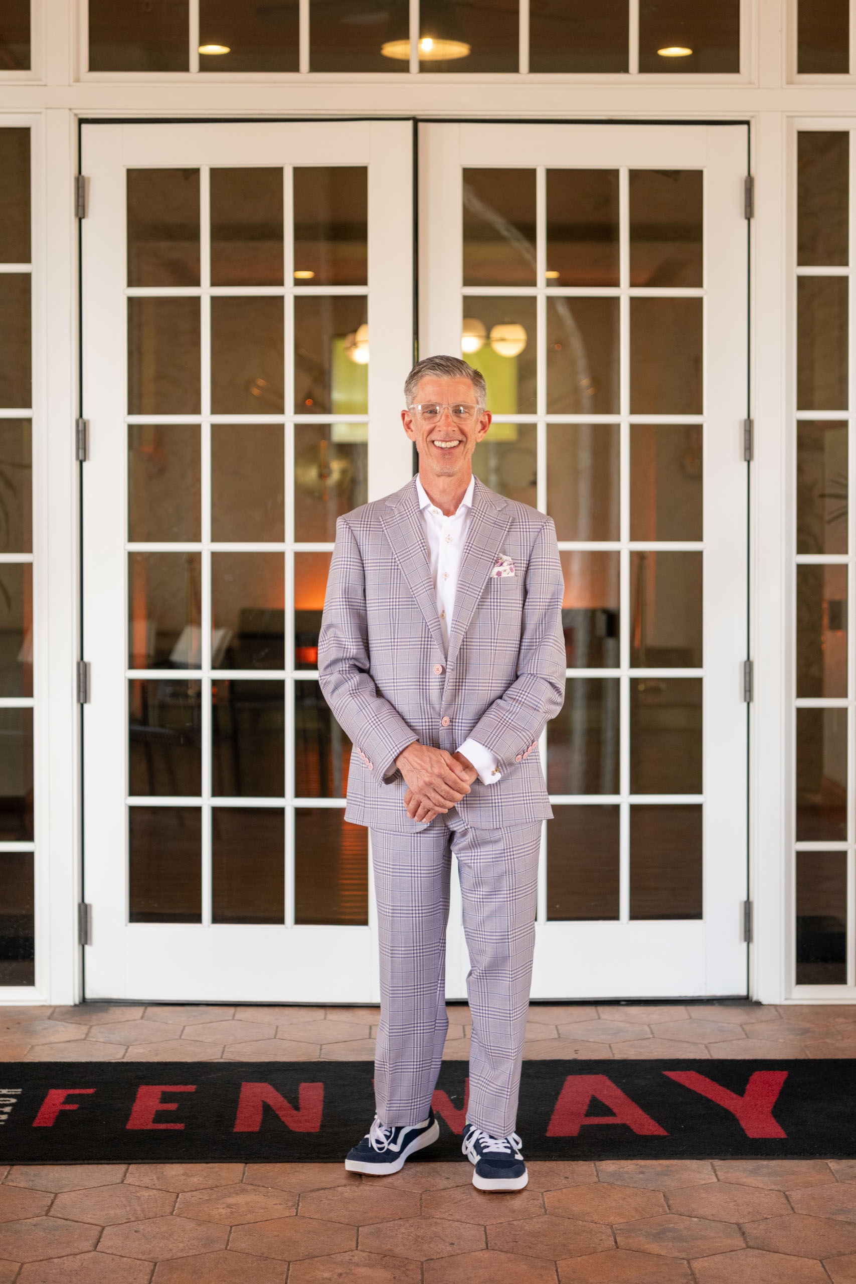 groom stands in front of the Fenway hotel doors