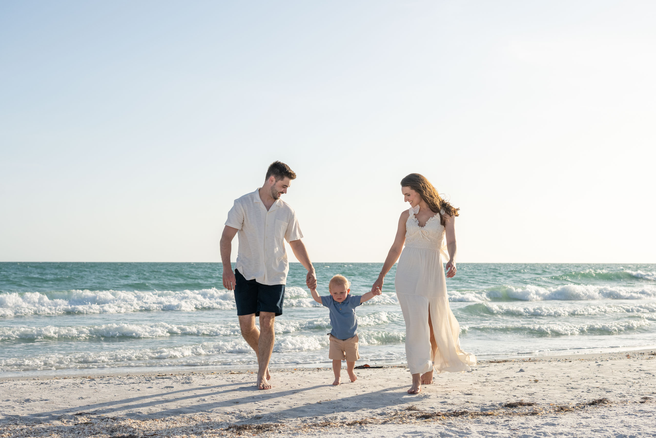 parents walking with their baby boy on the beach