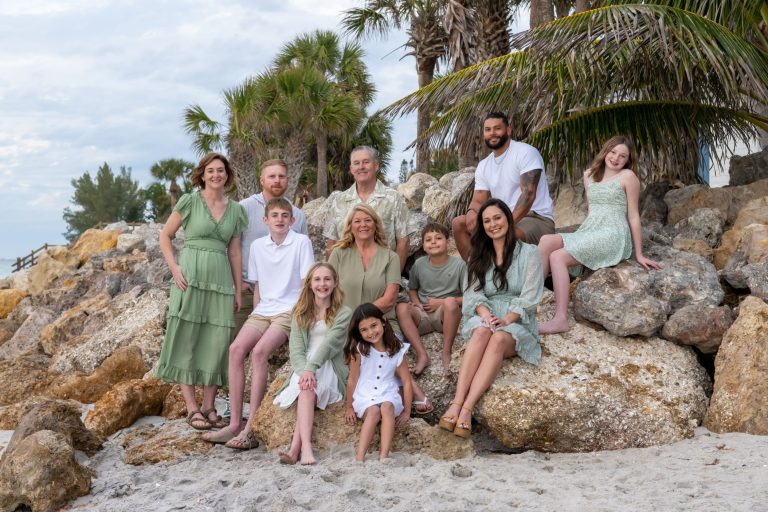 multigenerational family sitting on rocks all wearing shades of green