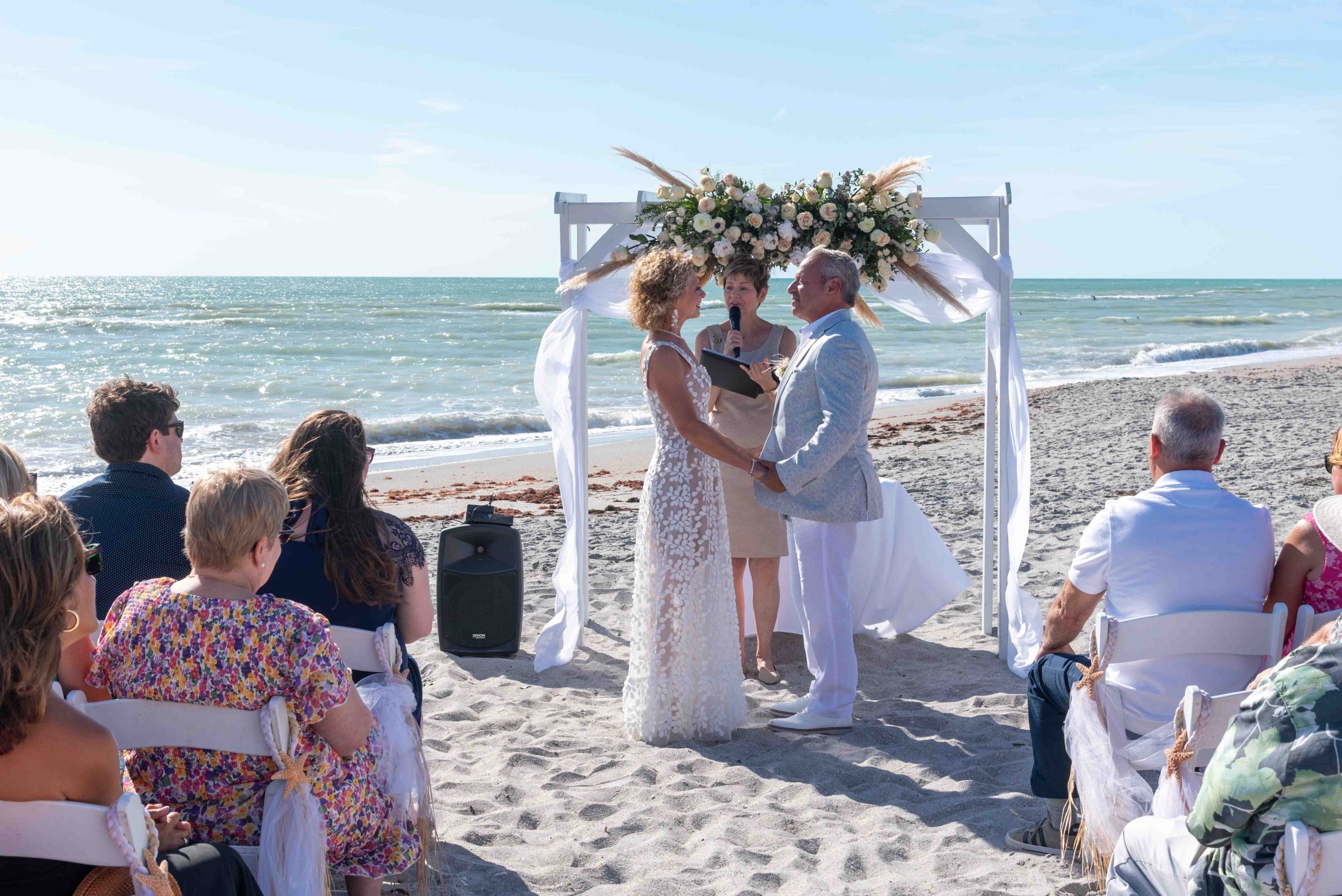 bride and groom hold hands at the altar during wedding on Englewood Beach