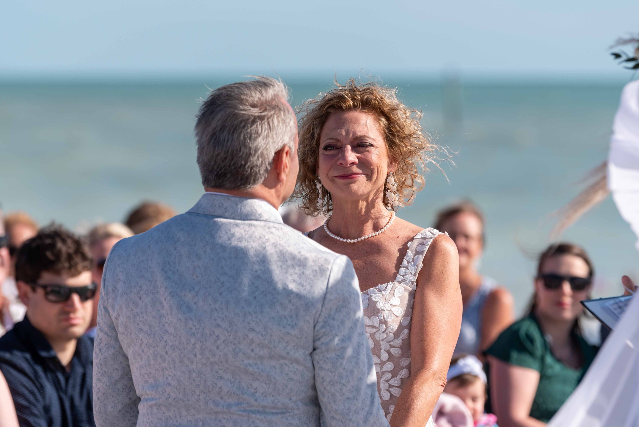 wife smiles at her husband during wedding ceremony on Englewood Beach on Manasota Key