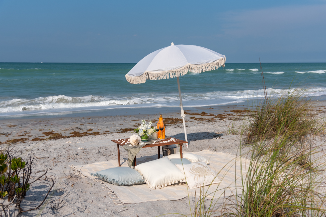 umbrella, pillows and beach blanket set up by water