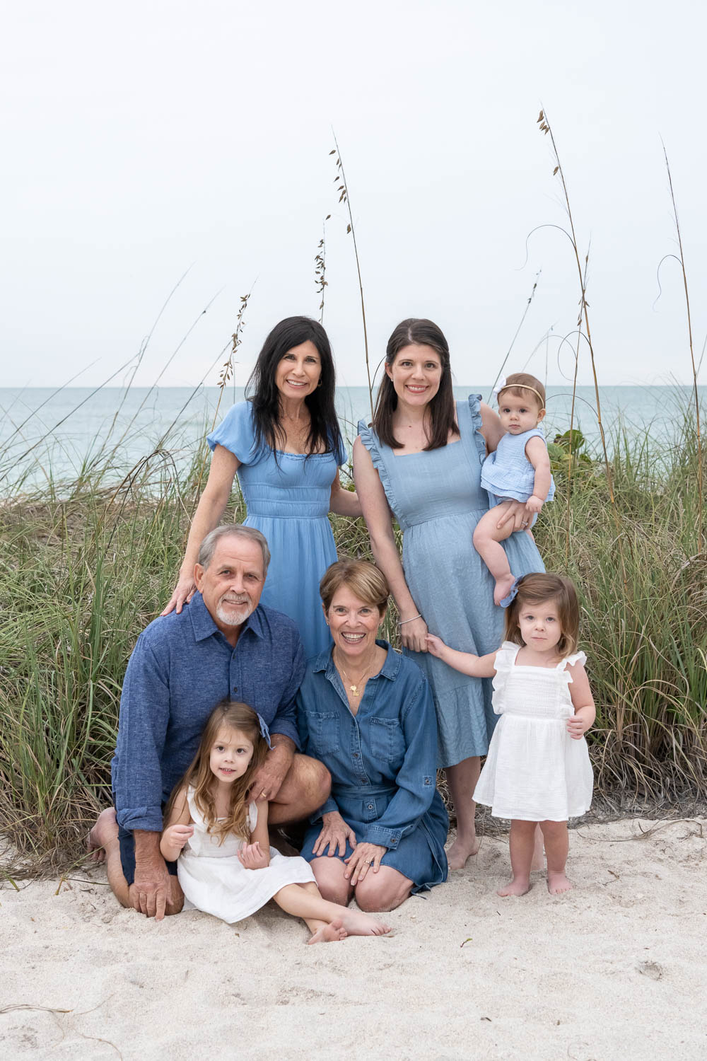 three generations of family sit together on the beach