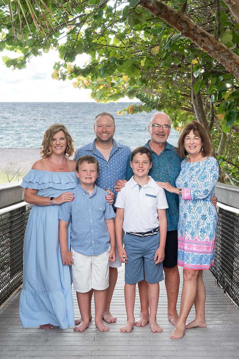 grandparents with their daughter and her sons stand on a boardwalk with the Gulf behind them