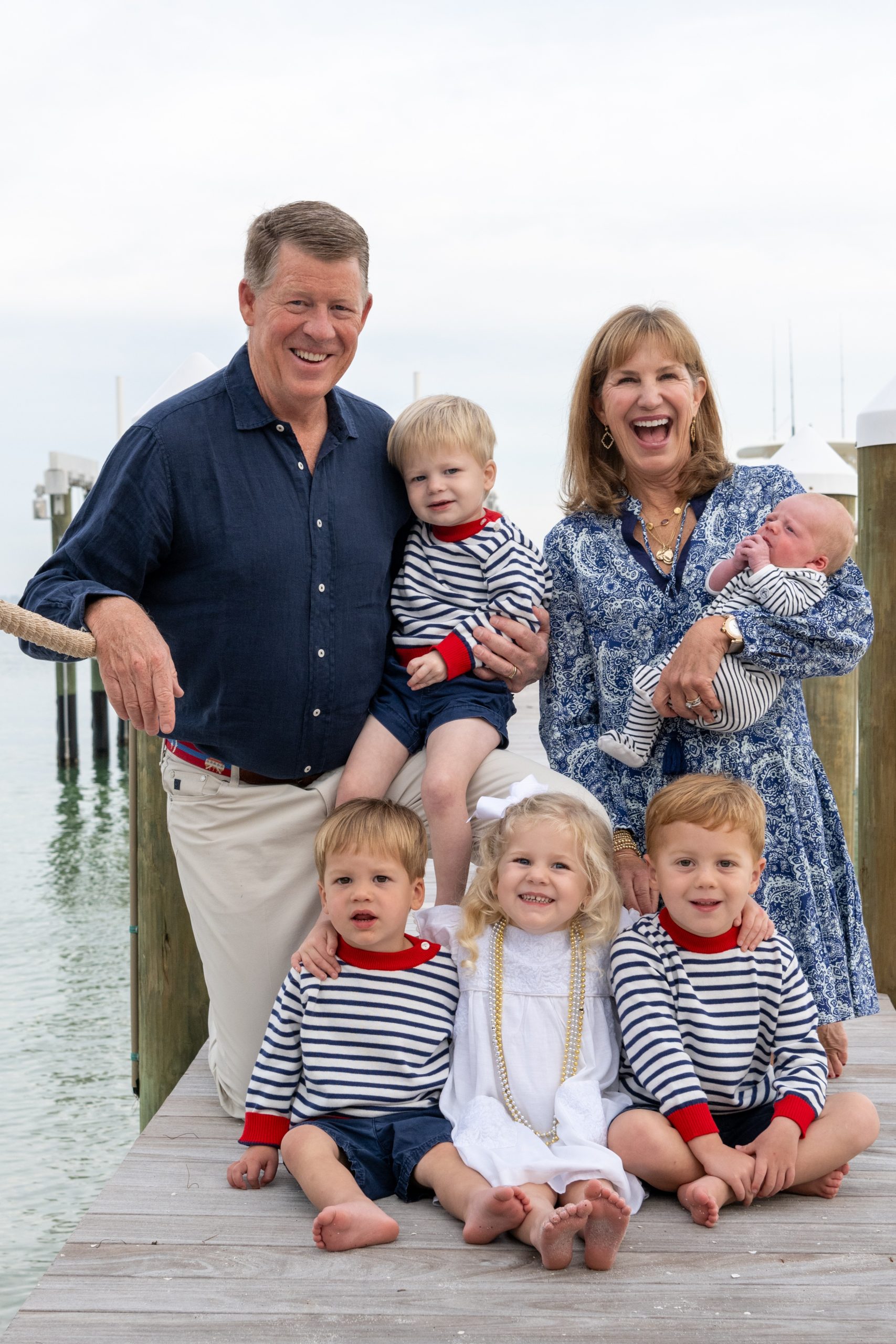 grandma and grandpa laugh as they are surrounded by their five grandchildren