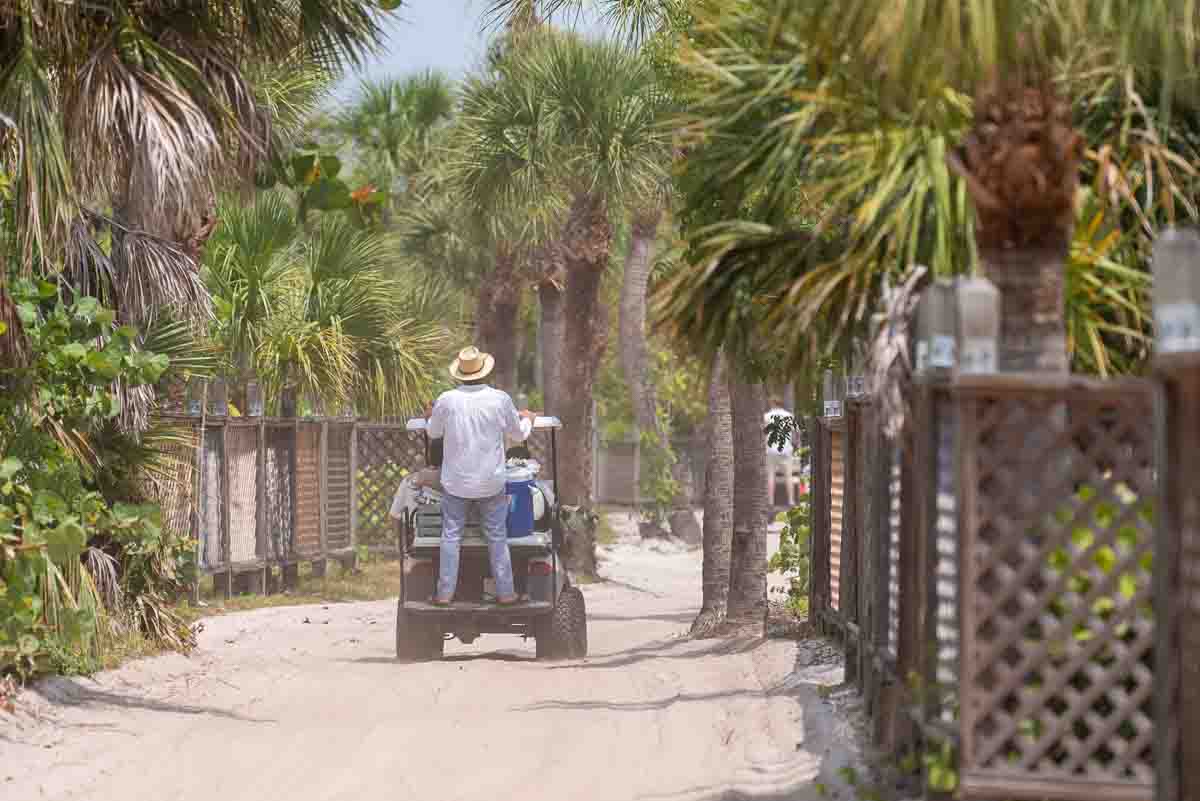 view as the golf cart pulls away with the groom standing on the back