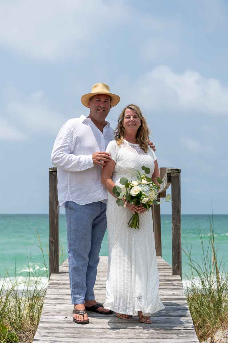 bride and groom stand on a boardwalk to take their wedding photos