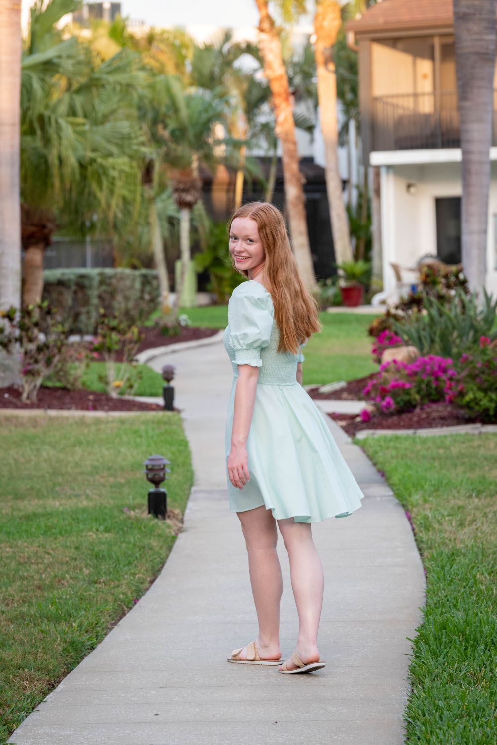 girl in aqua dress walking away on a curved sidewalk at Tamarind Inn on Manasota Key