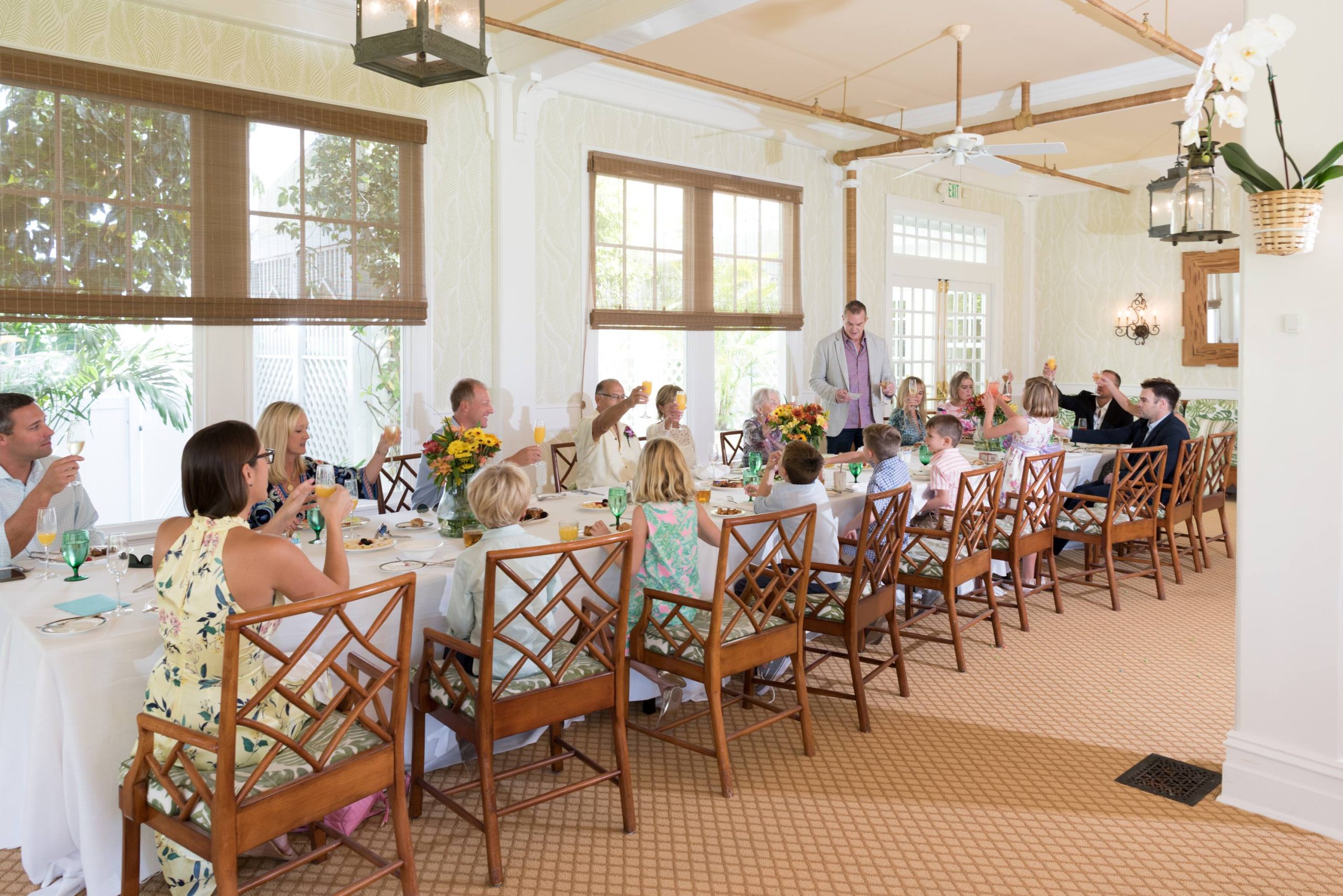 family sitting at brunch raising a glass of champagne to celebrate wedding