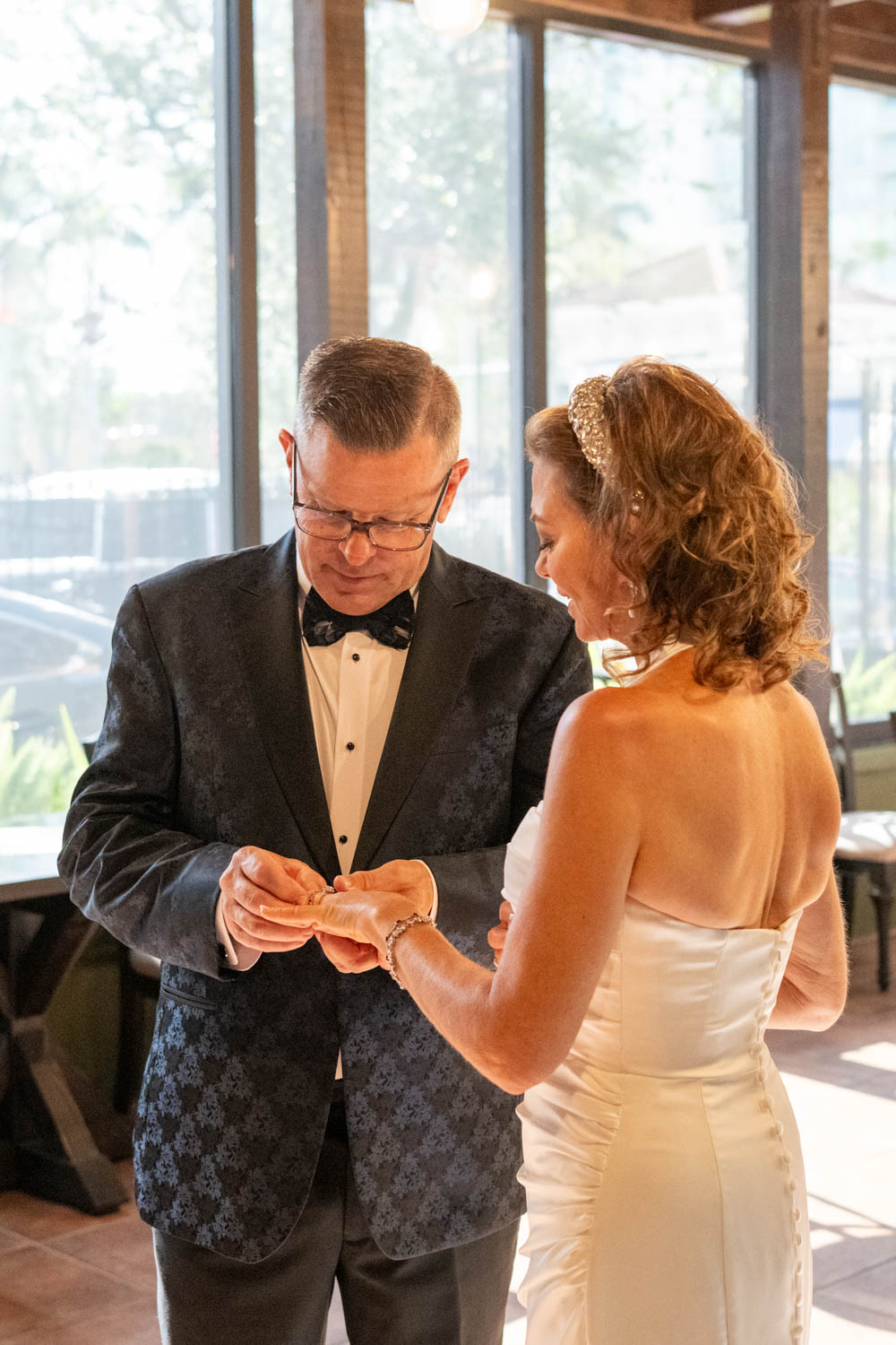 groom puts the bride's ring on her finger during wedding ceremony
