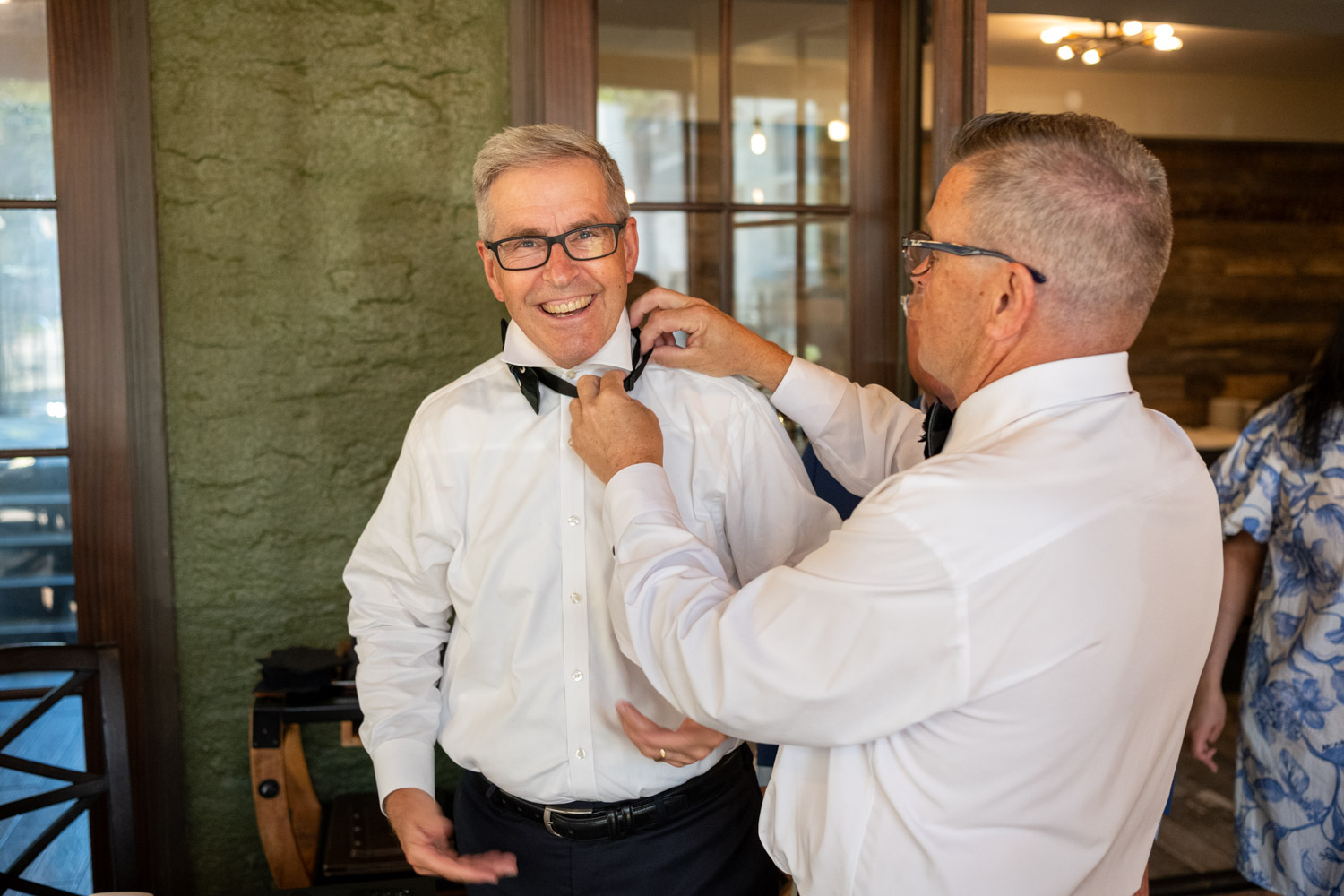 groom helps his best man and brother put on his bow tie before wedding