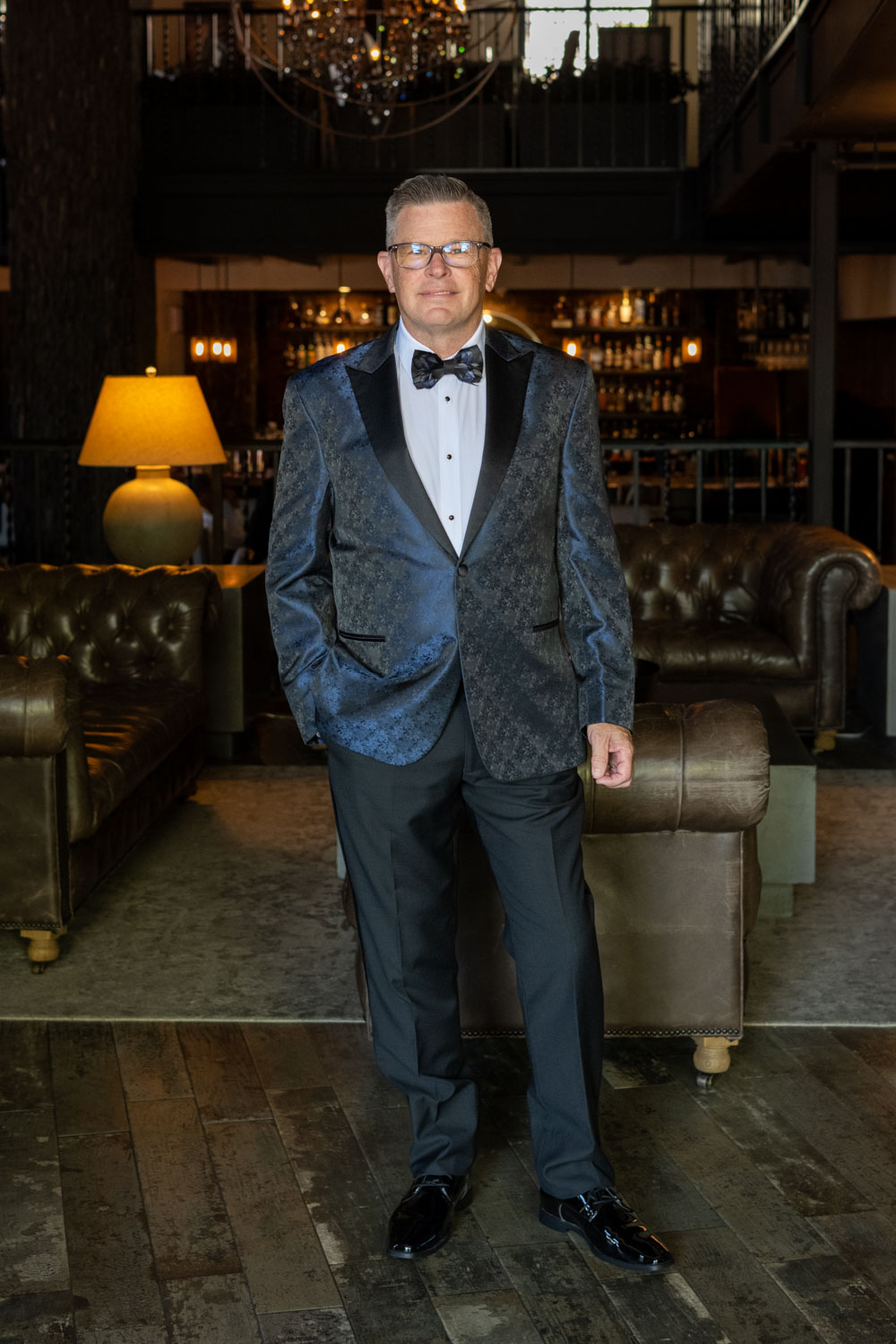the groom looks handsome in his blue tux in the lobby of Sage SRQ before the wedding
