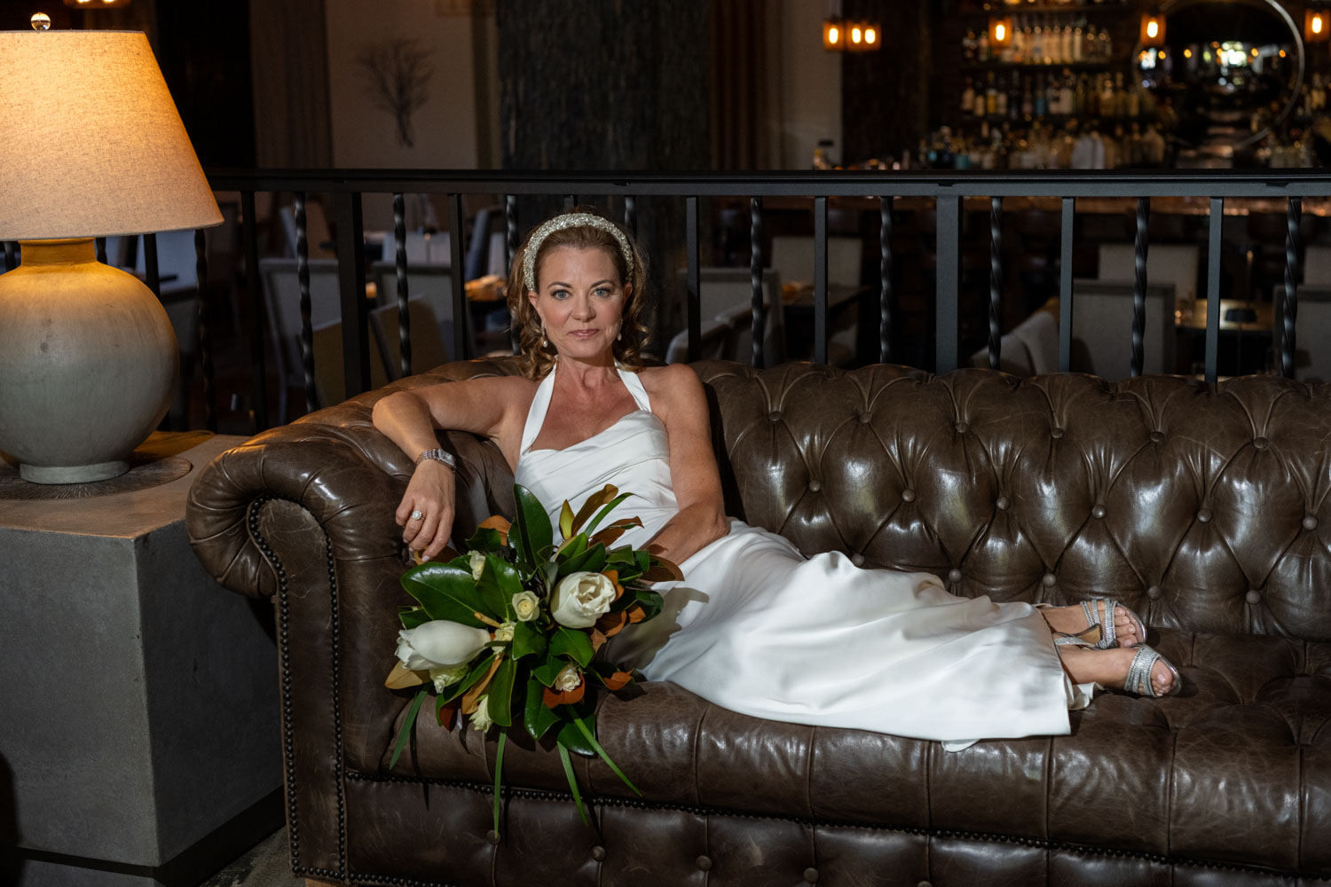 the bride lounges on the leather sofa in the lobby of Sage SRQ before their wedding