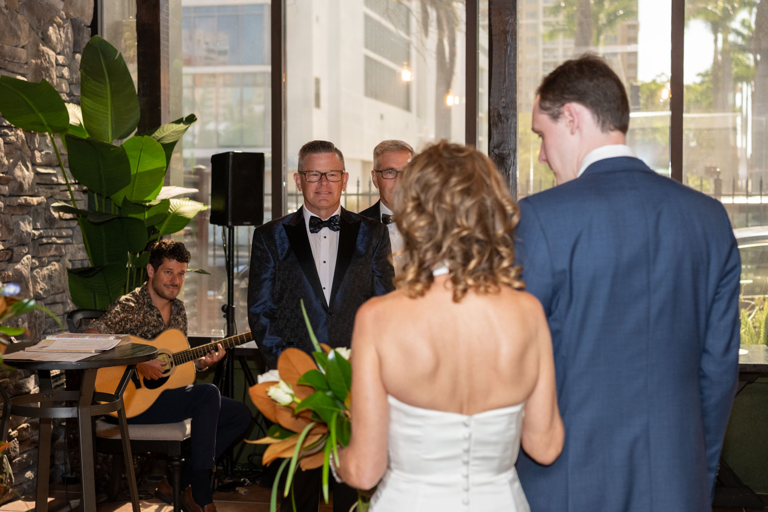 the groom watches his bride enter the room for the wedding