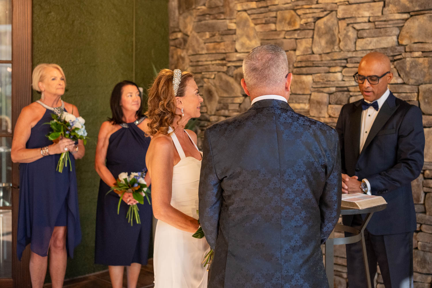 bride and groom stand with the officiant for their wedding