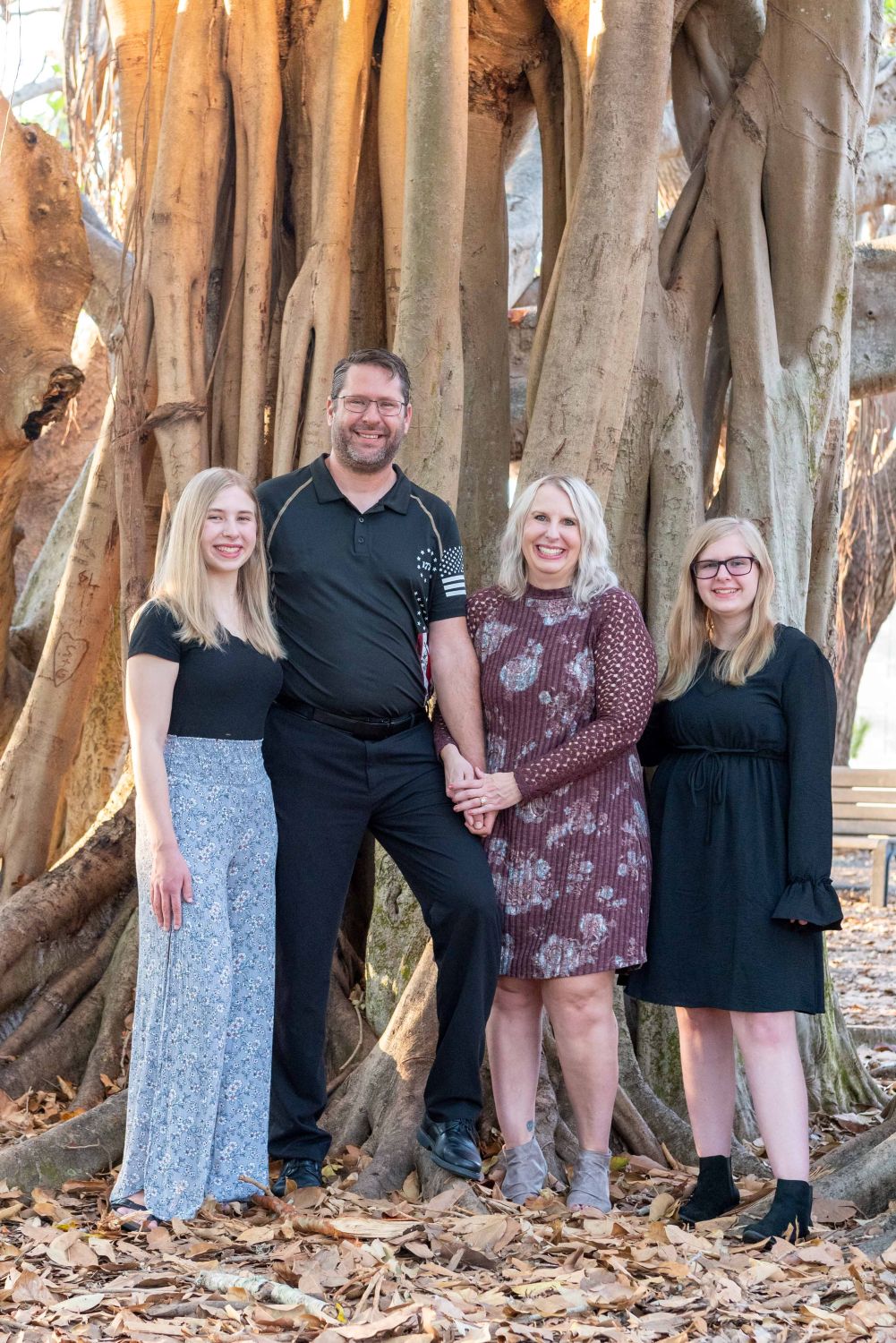 family with parents and two daughters in front of a Banyan tree