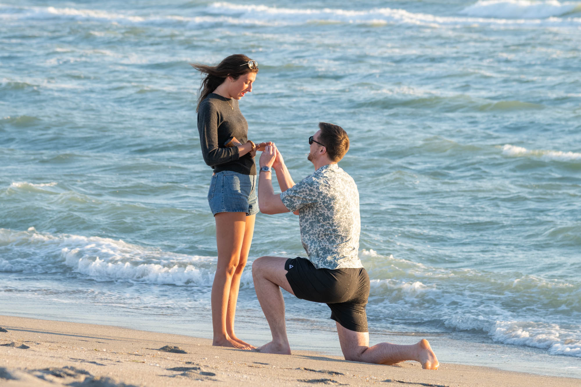 guy down on his knee proposing to his girlfriend on the beach