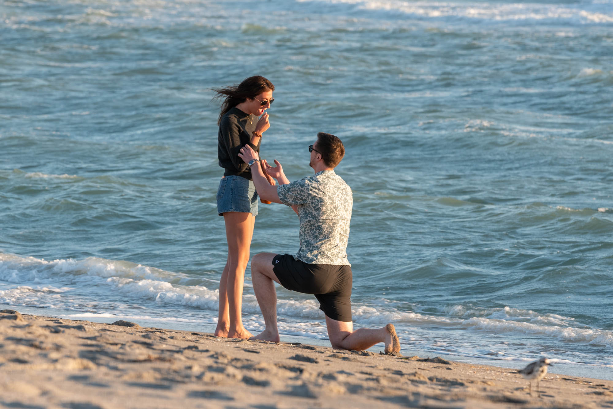 guy on his knee proposing to his girlfriend on the beach