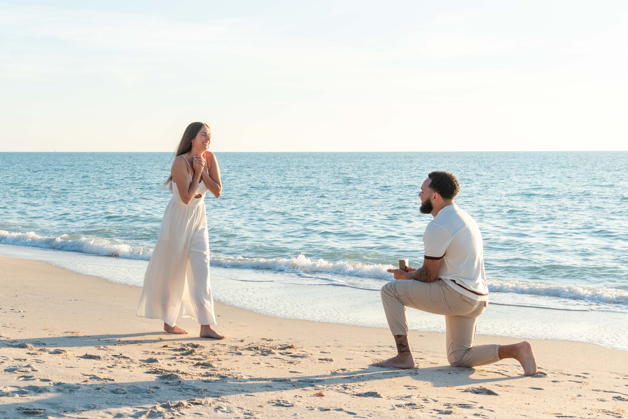 man down on his knee on the beach to propose to his girlfriend