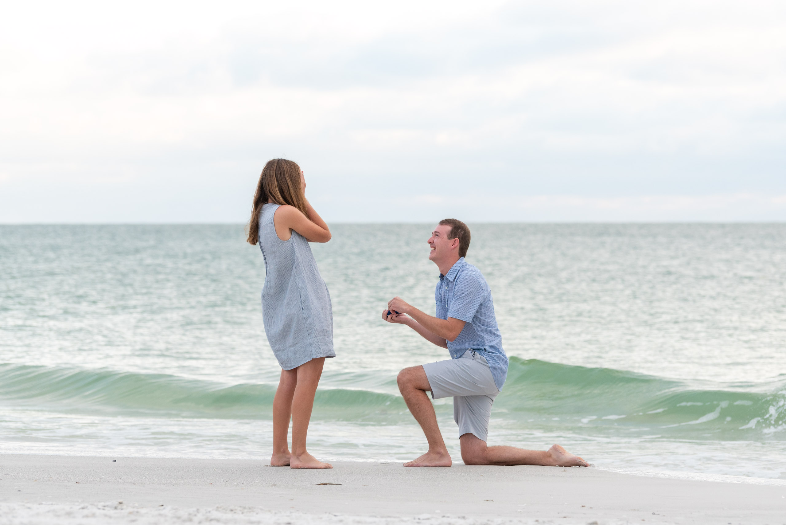 guy on his knee proposing to his girlfriend on the beach